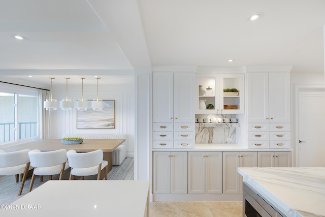 4545 S Atlantic Ave Unit 3604, Ponce Inlet, FL 32127 - kitchen with white cabinetry, glass insert cabinets, hanging light fixtures, recessed lighting, and light stone countertops
