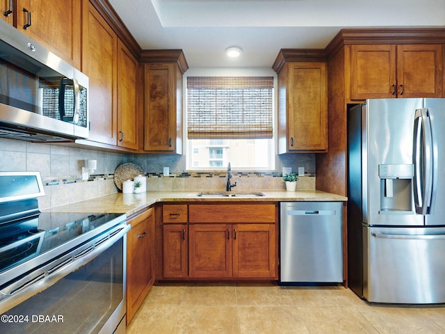 kitchen featuring backsplash, sink, light tile patterned floors, and stainless steel appliances