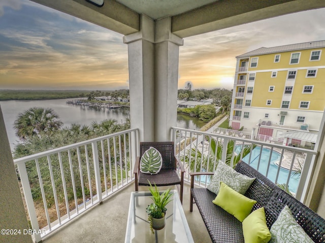 balcony at dusk featuring a water view