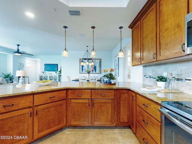 kitchen with ceiling fan with notable chandelier, decorative backsplash, decorative light fixtures, light stone counters, and kitchen peninsula