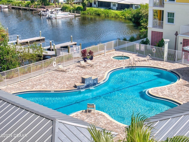 view of pool with a patio area, a water view, and a community hot tub