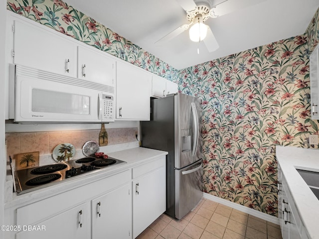 kitchen featuring white microwave, wallpapered walls, electric stovetop, and stainless steel fridge with ice dispenser