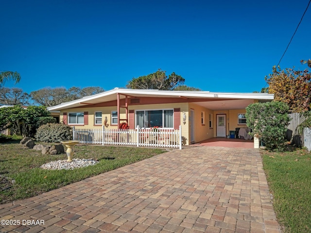 view of front of home featuring a carport, decorative driveway, and fence