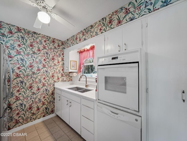 kitchen featuring white appliances, wallpapered walls, and a sink