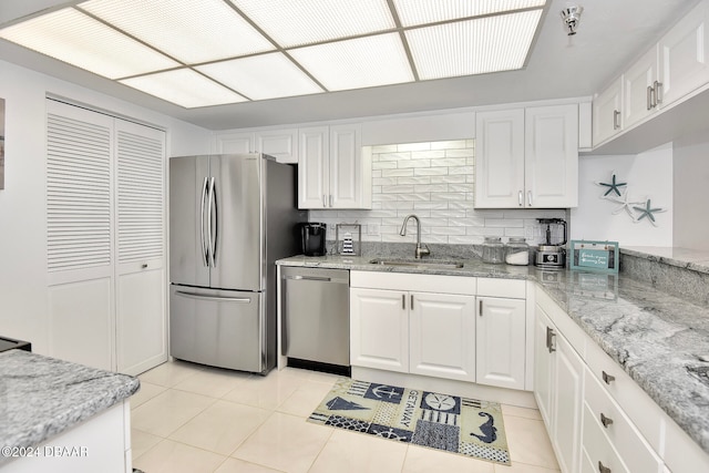 kitchen featuring stainless steel appliances, white cabinetry, tasteful backsplash, and sink