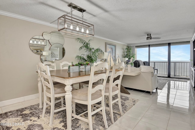 tiled dining space with a textured ceiling, a wall of windows, ceiling fan, and ornamental molding