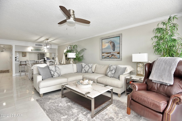 living room with light tile patterned floors, a textured ceiling, ceiling fan, and ornamental molding