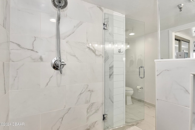 bathroom featuring toilet and a shower with shower door