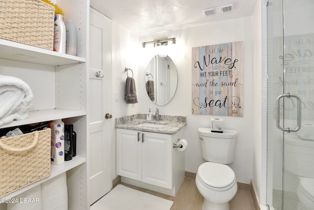 bathroom featuring vanity, toilet, and an enclosed shower