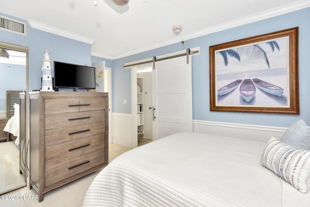 bedroom with ornamental molding, a textured ceiling, ceiling fan, light tile patterned floors, and a barn door