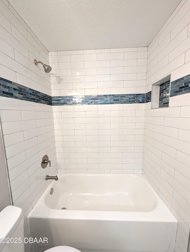 bathroom with tiled shower / bath, a textured ceiling, and toilet