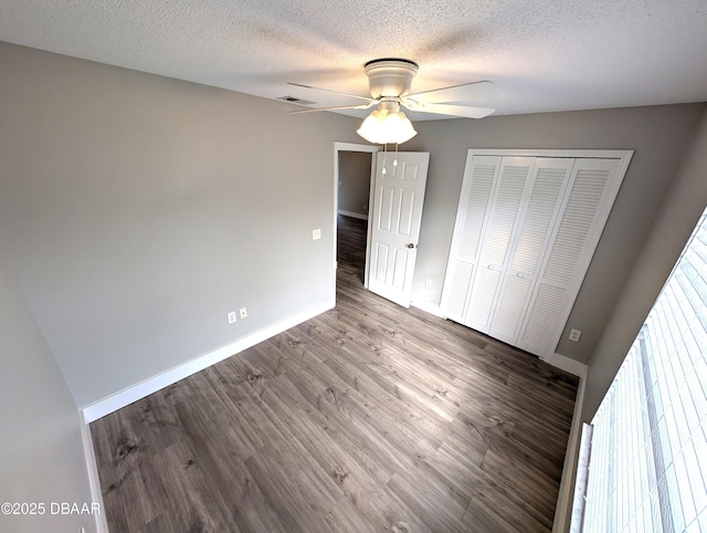 unfurnished bedroom with wood-type flooring, ceiling fan, a textured ceiling, and a closet