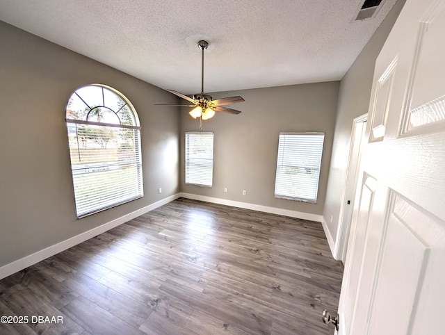 unfurnished dining area with ceiling fan, dark hardwood / wood-style floors, and a textured ceiling