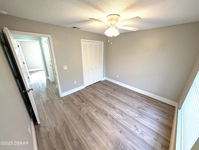 unfurnished bedroom with ceiling fan, light hardwood / wood-style floors, a closet, and a textured ceiling