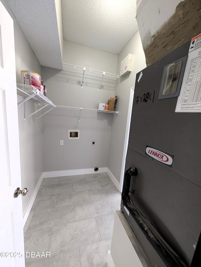 laundry room with hookup for a washing machine, hookup for an electric dryer, a textured ceiling, and light tile patterned flooring