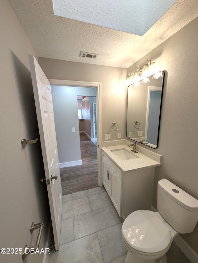 bathroom featuring vanity, toilet, and a textured ceiling