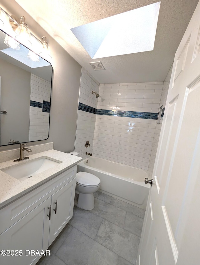 full bathroom with vanity, toilet, tiled shower / bath combo, and a textured ceiling