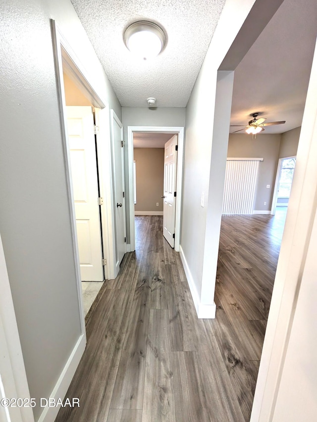 corridor with dark hardwood / wood-style floors and a textured ceiling