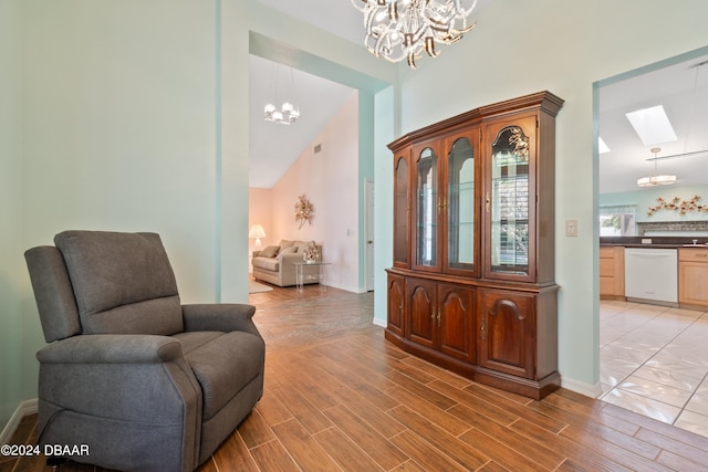 sitting room featuring a chandelier, light hardwood / wood-style flooring, and lofted ceiling with skylight