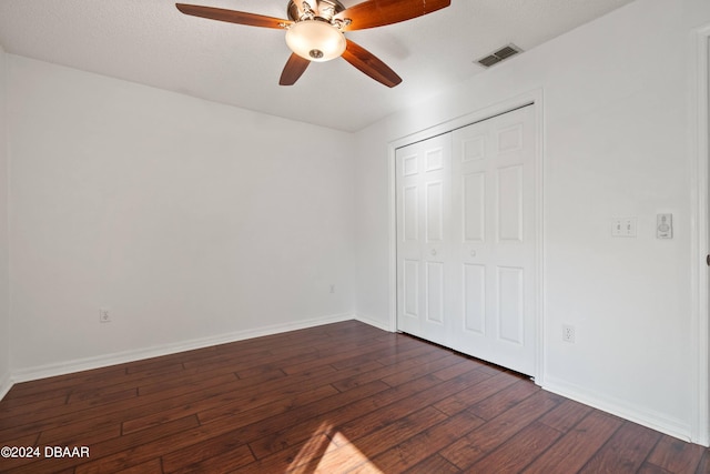 unfurnished bedroom featuring a textured ceiling, dark wood-type flooring, ceiling fan, and a closet