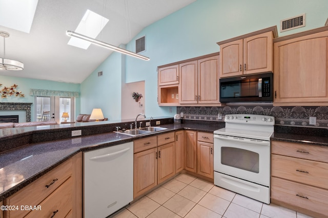 kitchen with sink, vaulted ceiling with skylight, light brown cabinetry, light tile patterned floors, and white appliances