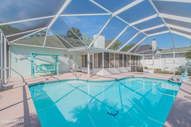 view of pool with glass enclosure, a sunroom, and a patio