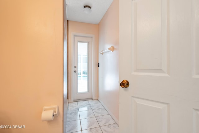 entryway with a wealth of natural light, a textured ceiling, and light tile patterned floors