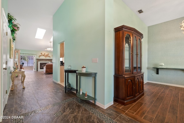 hall featuring dark wood-type flooring and vaulted ceiling with skylight