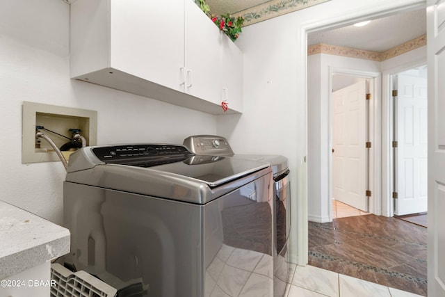 washroom with washing machine and dryer, cabinets, and a textured ceiling