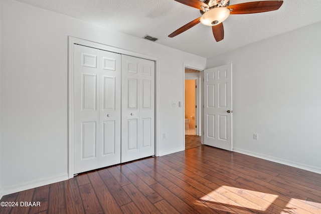 unfurnished bedroom with dark hardwood / wood-style flooring, a closet, a textured ceiling, and ceiling fan