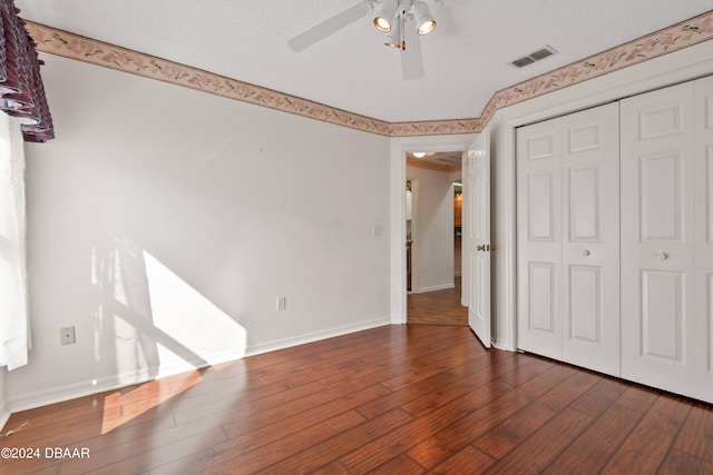 unfurnished bedroom with a textured ceiling, dark hardwood / wood-style floors, ceiling fan, and a closet