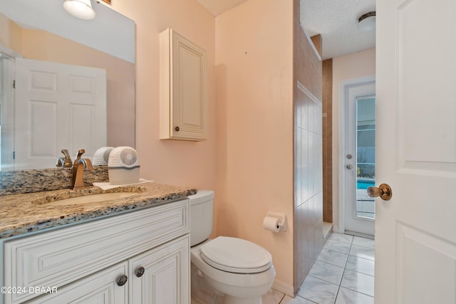 bathroom featuring toilet, vanity, a textured ceiling, and tile patterned flooring