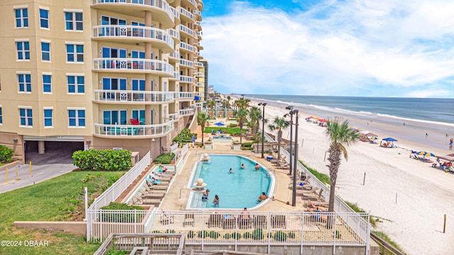 view of swimming pool with a beach view and a water view