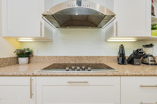 kitchen featuring white cabinets, black electric cooktop, light stone counters, and exhaust hood