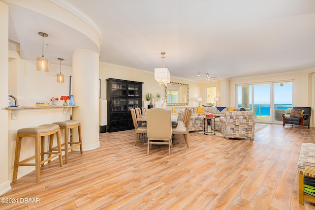 dining area featuring light wood-type flooring, a water view, and crown molding