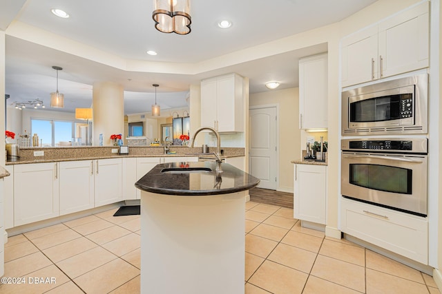1925 S Atlantic Ave Unit 806, Daytona Beach Shores, FL 32118 - kitchen featuring stainless steel appliances, a sink, light tile patterned floors, dark stone counters, and white cabinetry