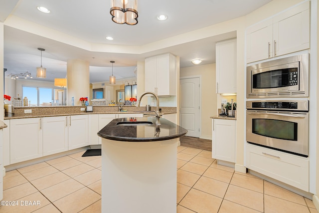 kitchen featuring kitchen peninsula, hanging light fixtures, sink, white cabinetry, and appliances with stainless steel finishes