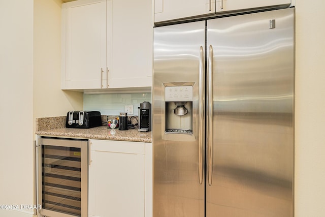 1925 S Atlantic Ave Unit 806, Daytona Beach Shores, FL 32118 - kitchen featuring stainless steel refrigerator with ice dispenser, wine cooler, white cabinets, and light stone countertops