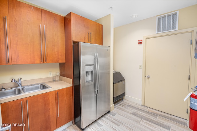 kitchen featuring stainless steel fridge with ice dispenser, sink, and light wood-type flooring