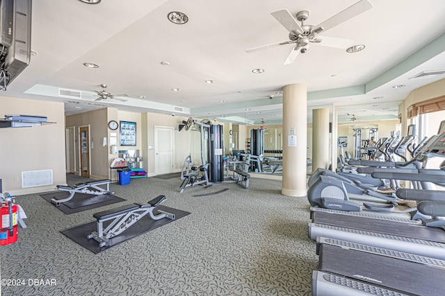 exercise room featuring carpet floors, ceiling fan, and a raised ceiling