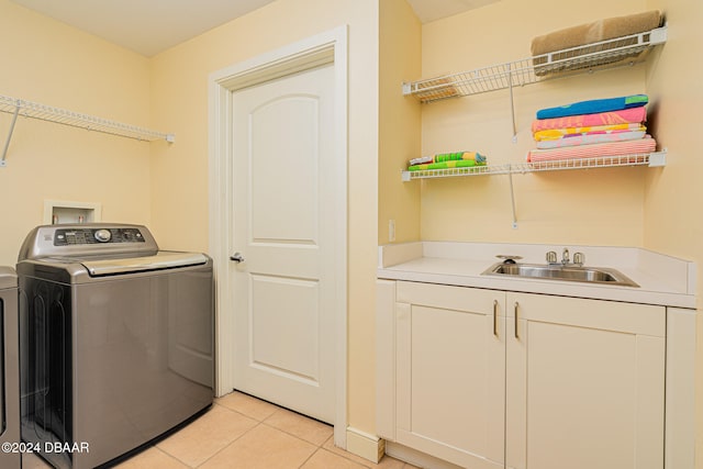 clothes washing area featuring washer / clothes dryer, cabinets, sink, and light tile patterned flooring