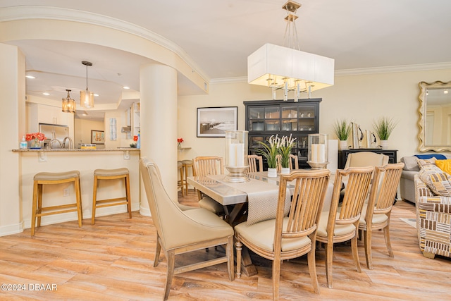 dining space featuring ornamental molding and light hardwood / wood-style flooring