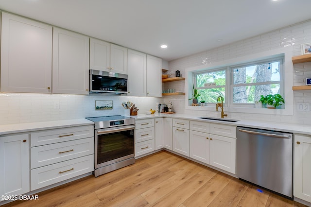kitchen with a sink, stainless steel appliances, open shelves, white cabinetry, and backsplash