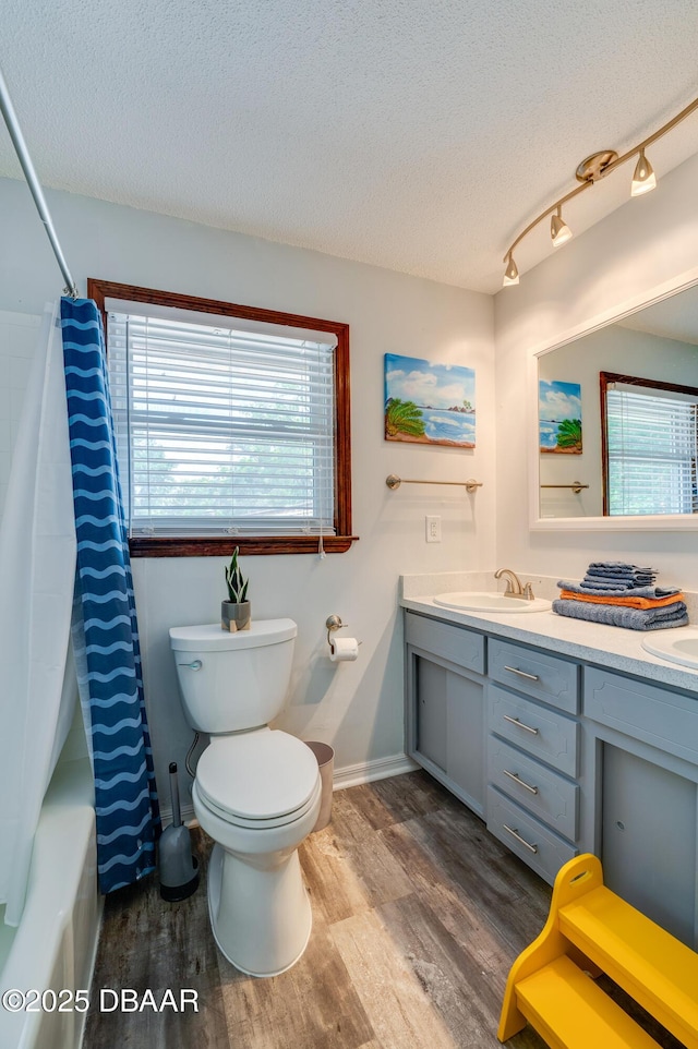 full bath with a wealth of natural light, a sink, and wood finished floors