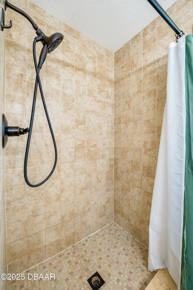 bathroom with a textured ceiling and tiled shower