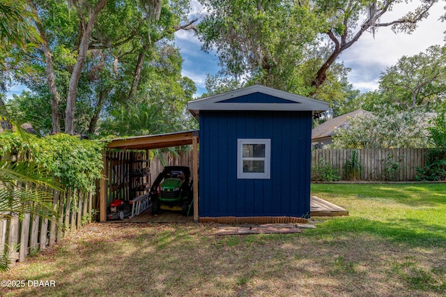 view of shed featuring a carport and a fenced backyard