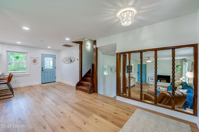 foyer featuring light wood-style flooring, stairs, baseboards, and visible vents