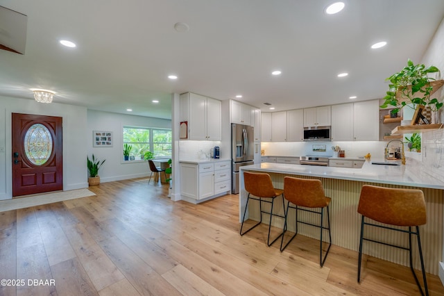 kitchen featuring a sink, a peninsula, open shelves, decorative backsplash, and appliances with stainless steel finishes