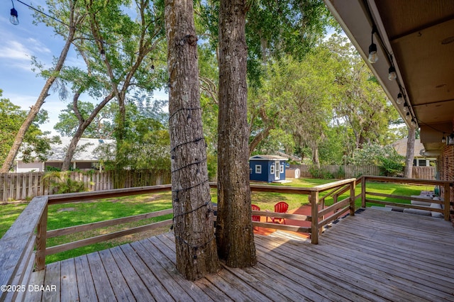 deck with a fenced backyard, a lawn, a shed, and an outbuilding