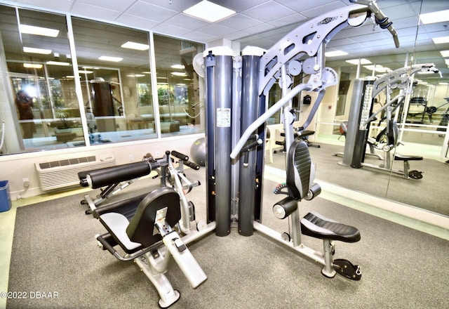 gym featuring a paneled ceiling and a wall mounted AC